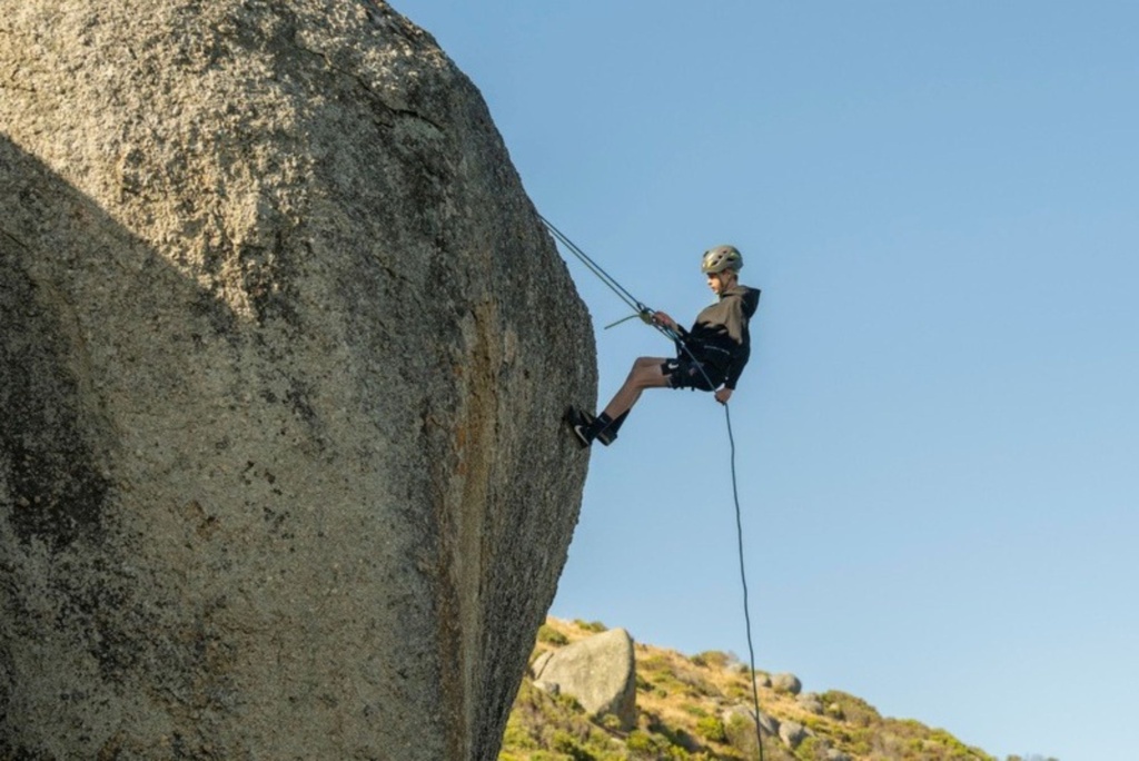 A person abseiling down The Bluff with Surf & Sun